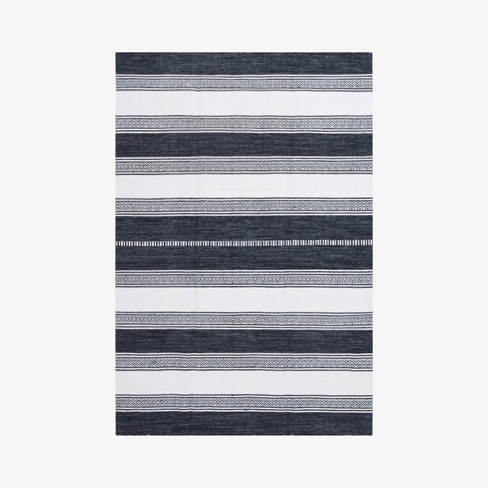 שטיח באריגה שטוחה בדוגמאת פסים בגוונים של שחור ולבן עם פסים בדוגמאות גיאומטריות לסירוגין